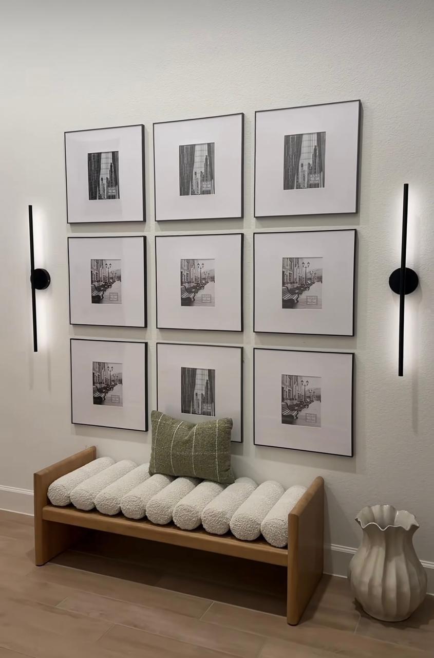 Symmetrical black and white gallery wall above a bouclé bench